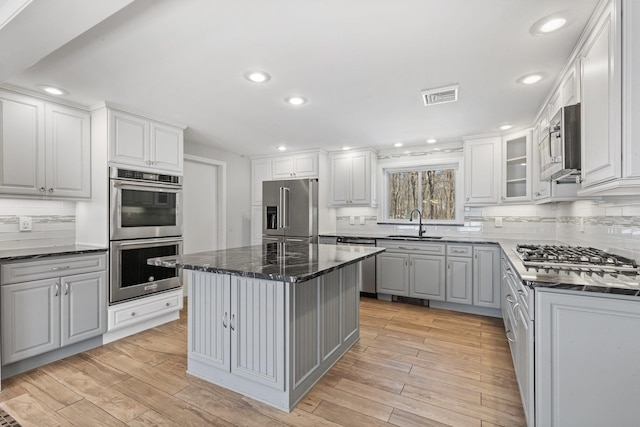 kitchen with appliances with stainless steel finishes, visible vents, a sink, and light wood-style flooring