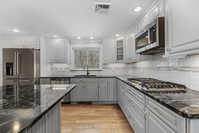 kitchen featuring stainless steel appliances, a sink, visible vents, and decorative backsplash