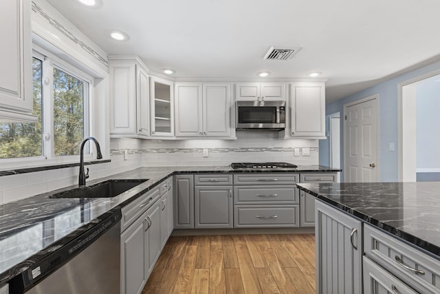 kitchen with stainless steel appliances, gray cabinets, visible vents, light wood-style floors, and a sink