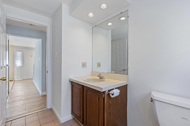 bathroom featuring recessed lighting, toilet, vanity, tile patterned flooring, and baseboards