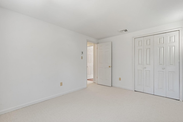 unfurnished bedroom featuring light carpet, baseboards, visible vents, and a closet