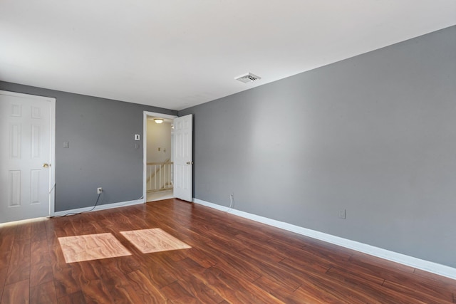 spare room featuring wood finished floors, visible vents, and baseboards