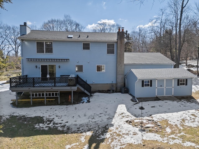 snow covered rear of property with a chimney, a wooden deck, and central air condition unit