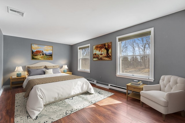 bedroom with wood finished floors, visible vents, and baseboards