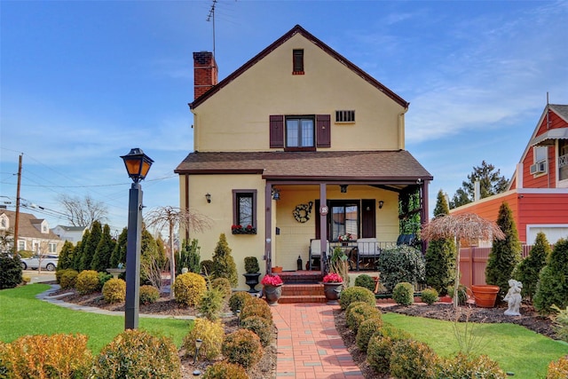 view of front of home featuring a porch, roof with shingles, a front lawn, and stucco siding