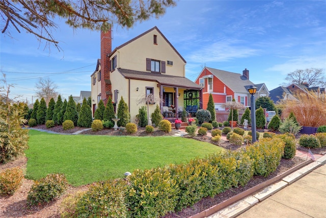 view of front of property featuring a front yard, covered porch, a chimney, and stucco siding