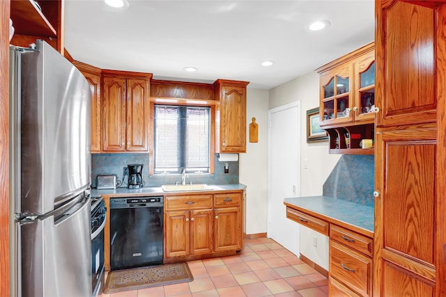 kitchen featuring a sink, light countertops, freestanding refrigerator, dishwasher, and glass insert cabinets