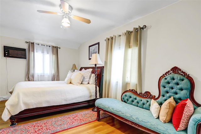 bedroom with lofted ceiling, wood finished floors, ceiling fan, and a wall mounted AC