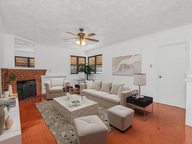 living area featuring a fireplace, a ceiling fan, and a textured ceiling