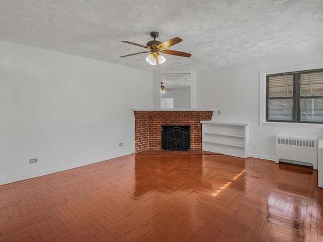 unfurnished living room with a ceiling fan, a brick fireplace, a textured ceiling, and radiator heating unit