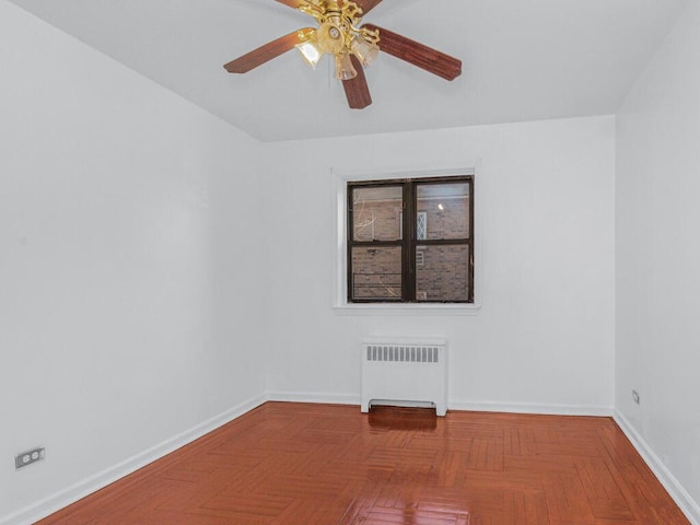 unfurnished room featuring baseboards, ceiling fan, and radiator