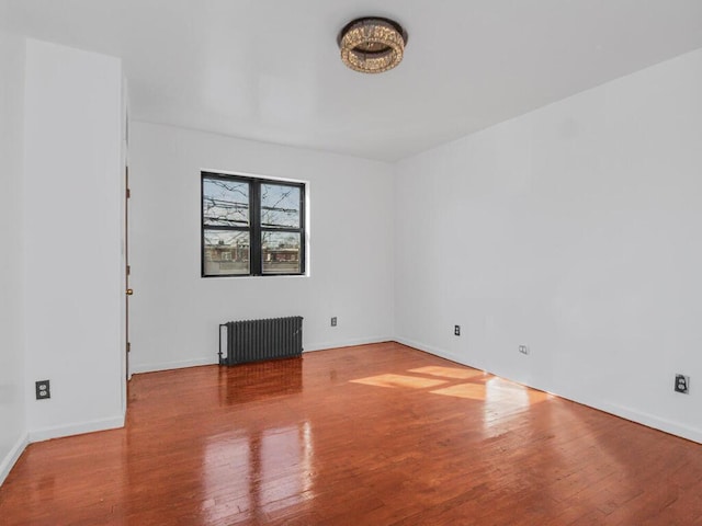 unfurnished room featuring radiator, baseboards, and wood finished floors