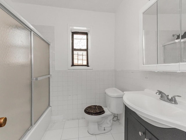 bathroom featuring tile walls, toilet, enclosed tub / shower combo, vanity, and tile patterned floors