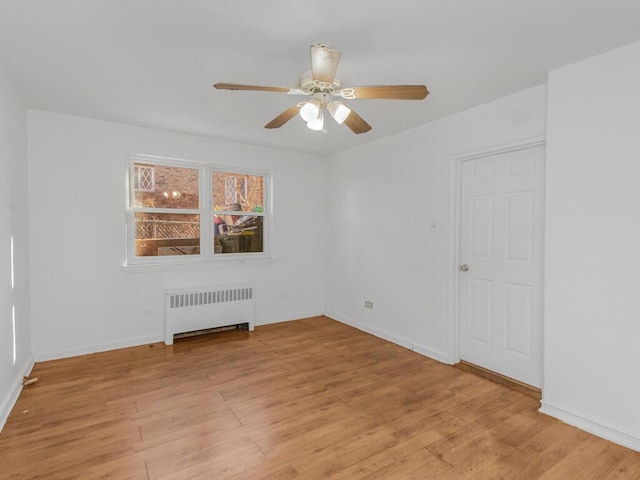 unfurnished room featuring baseboards, radiator heating unit, a ceiling fan, and light wood-style floors