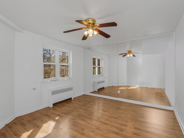 unfurnished room featuring radiator heating unit, wood finished floors, and a ceiling fan