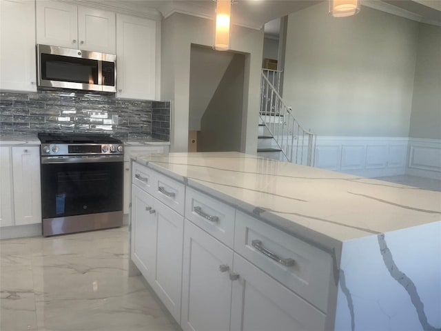 kitchen with tasteful backsplash, appliances with stainless steel finishes, light stone counters, marble finish floor, and white cabinetry