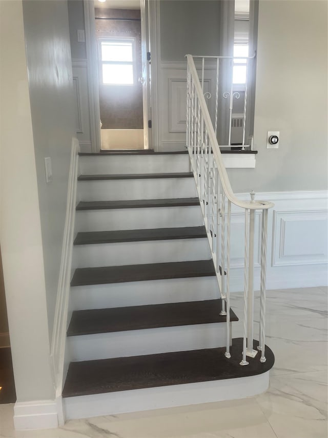 stairway featuring a wainscoted wall and a decorative wall