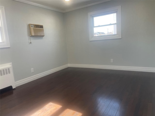 spare room featuring crown molding, radiator, a wall mounted AC, dark wood-type flooring, and baseboards