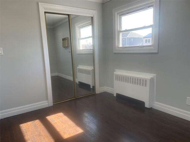 unfurnished bedroom with radiator, baseboards, and dark wood-style flooring