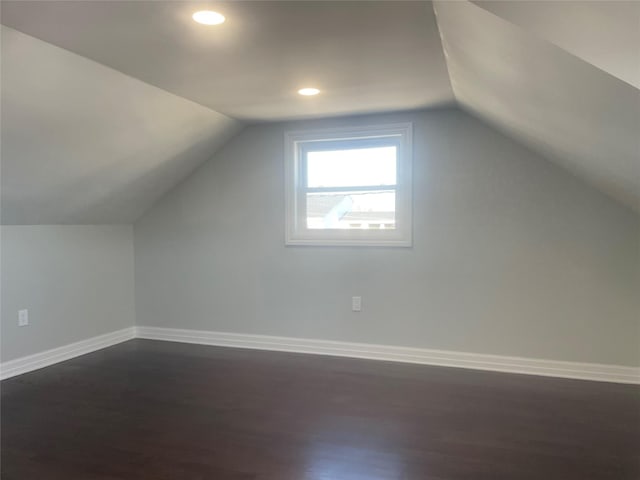 additional living space featuring baseboards, vaulted ceiling, dark wood-type flooring, and recessed lighting