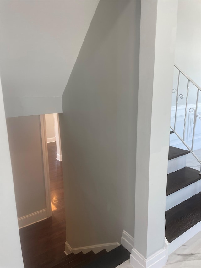 stairway with vaulted ceiling, wood finished floors, and baseboards