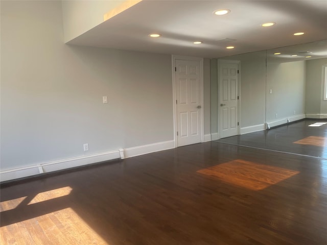 spare room featuring a baseboard radiator, dark wood finished floors, baseboards, and recessed lighting