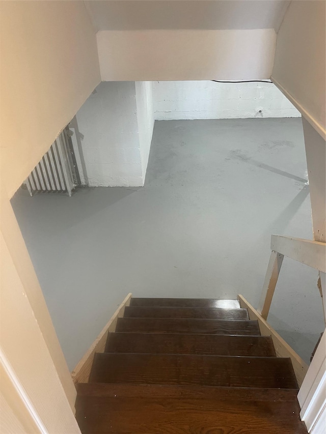 staircase featuring concrete flooring and vaulted ceiling