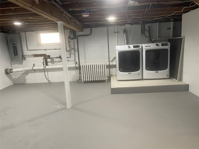 basement featuring radiator, electric panel, and washer and dryer