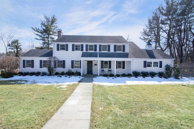 view of front of home with a chimney, a lawn, and roof with shingles