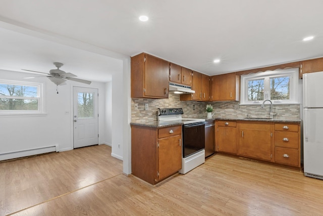 kitchen featuring light wood-style flooring, freestanding refrigerator, under cabinet range hood, a sink, and range with electric stovetop