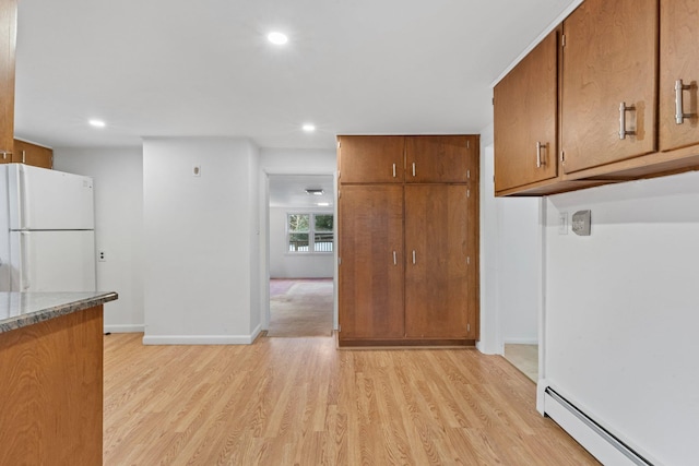 kitchen featuring light wood finished floors, a baseboard heating unit, brown cabinetry, and freestanding refrigerator