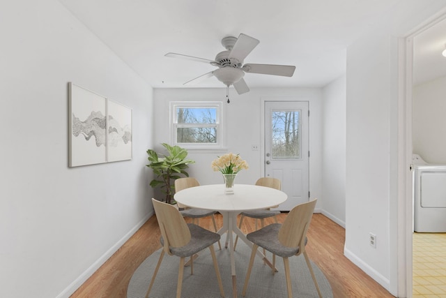 dining room featuring light wood-style flooring, washer / clothes dryer, ceiling fan, and baseboards