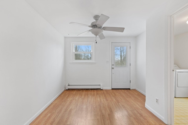 interior space with baseboards, a ceiling fan, light wood-style flooring, washer / clothes dryer, and baseboard heating