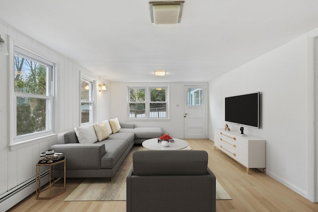 living area featuring light wood-style flooring, baseboard heating, and a wealth of natural light