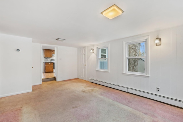 unfurnished room featuring a baseboard heating unit and light carpet