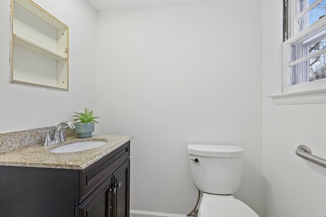 half bath featuring toilet, baseboards, and vanity