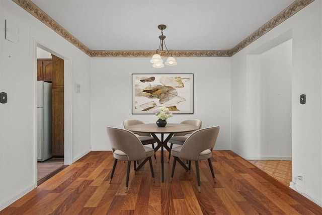 dining room featuring dark wood-type flooring, a notable chandelier, and baseboards