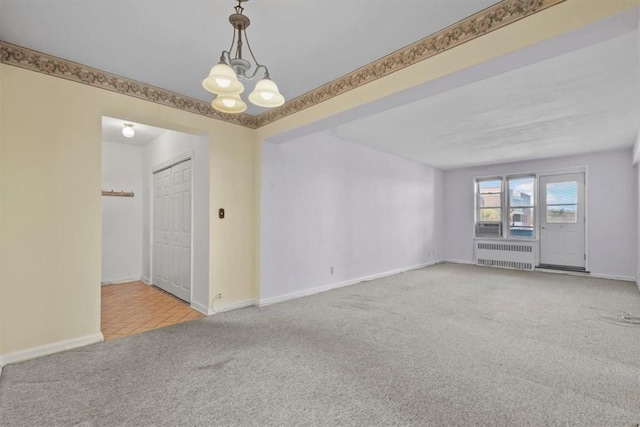 spare room featuring baseboards, light colored carpet, a notable chandelier, and radiator heating unit