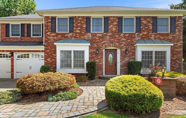 colonial inspired home with an attached garage and brick siding