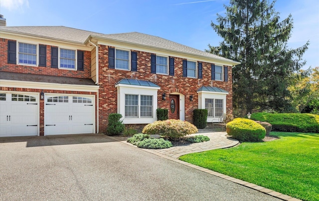 view of front of home with a garage, brick siding, aphalt driveway, roof with shingles, and a front yard