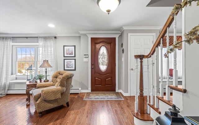 entrance foyer with a baseboard heating unit, crown molding, baseboards, and wood finished floors