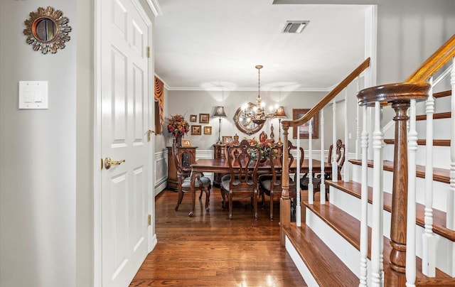 dining room with crown molding, visible vents, an inviting chandelier, wood finished floors, and stairs