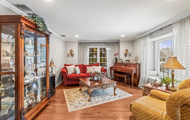 living room featuring wood finished floors, visible vents, and crown molding