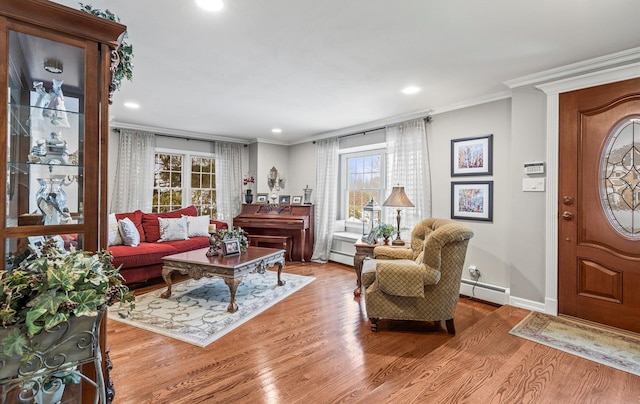 living area featuring baseboards, crown molding, baseboard heating, and wood finished floors