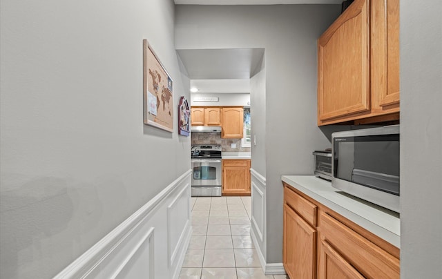 kitchen featuring light tile patterned floors, light countertops, decorative backsplash, appliances with stainless steel finishes, and under cabinet range hood