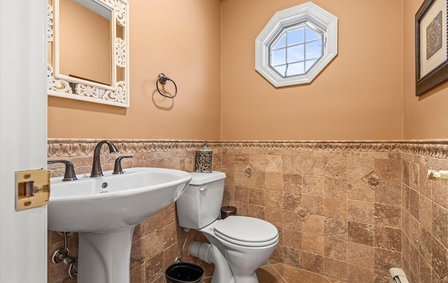 bathroom featuring wainscoting, toilet, and tile walls