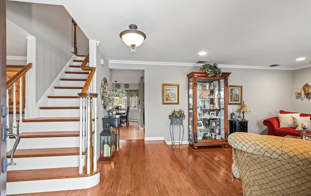 entryway featuring wood finished floors, visible vents, baseboards, stairs, and crown molding