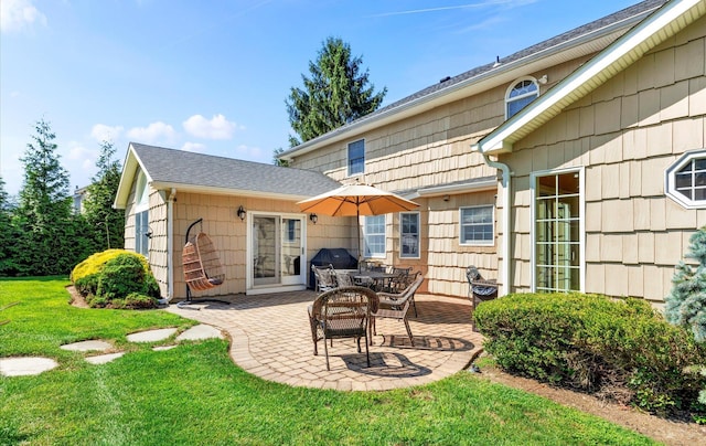 rear view of property with a patio, a lawn, and roof with shingles