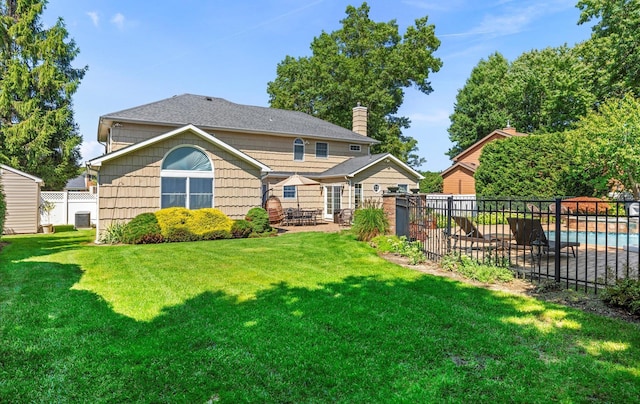 rear view of house with a patio area, fence, a fenced in pool, and a yard