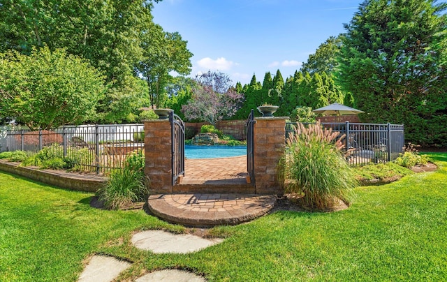 view of gate with a yard, fence, and a fenced in pool